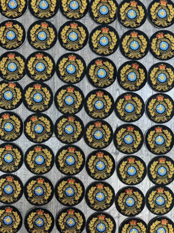 Patterned display of circular emblems featuring a blue and gold design, surrounded by laurel leaves and a crown, likely representing a decorative product for home décor.