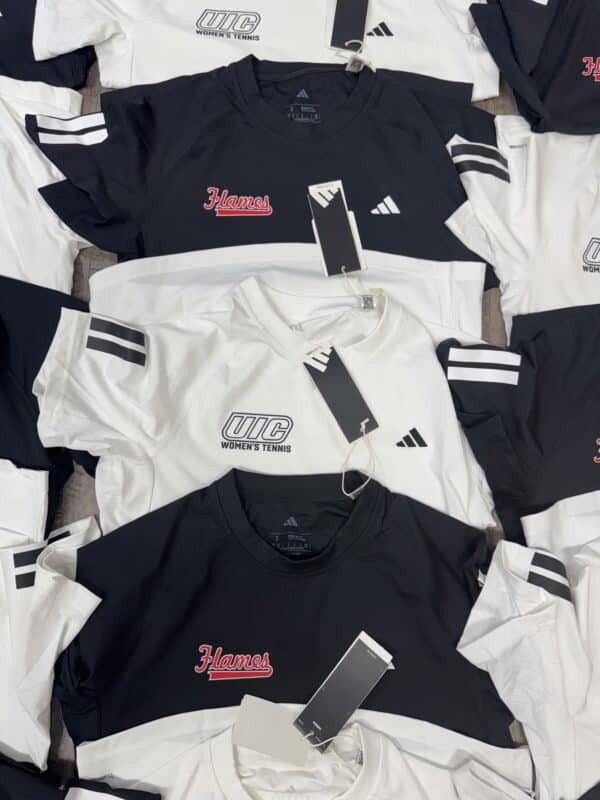 UIC Women’s Tennis apparel featuring black and white shirts with "Flames" logo, Adidas branding, and price tags, displayed in a retail setting.