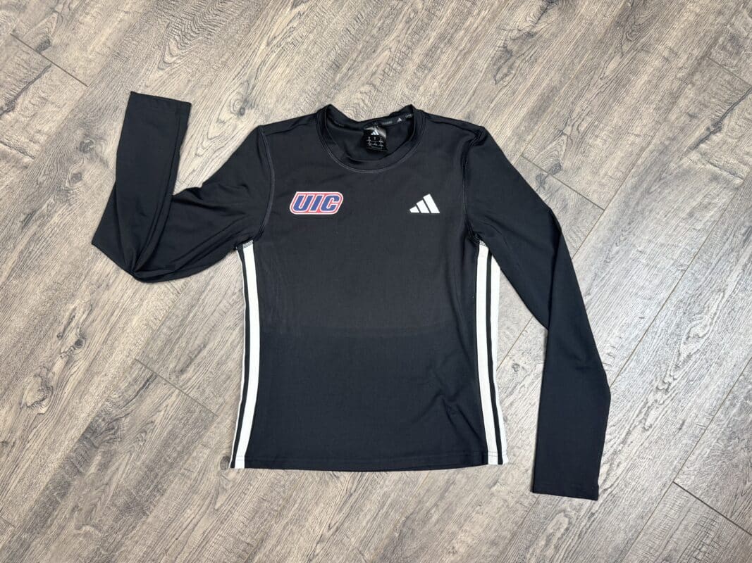 Black long-sleeve athletic shirt featuring UIC logo and Adidas branding, displayed on a wooden surface.