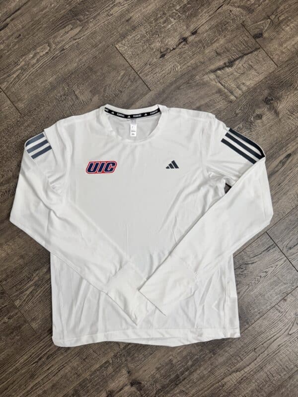 Long-sleeve white athletic shirt with UIC logo and Adidas branding, displayed on wooden floor.